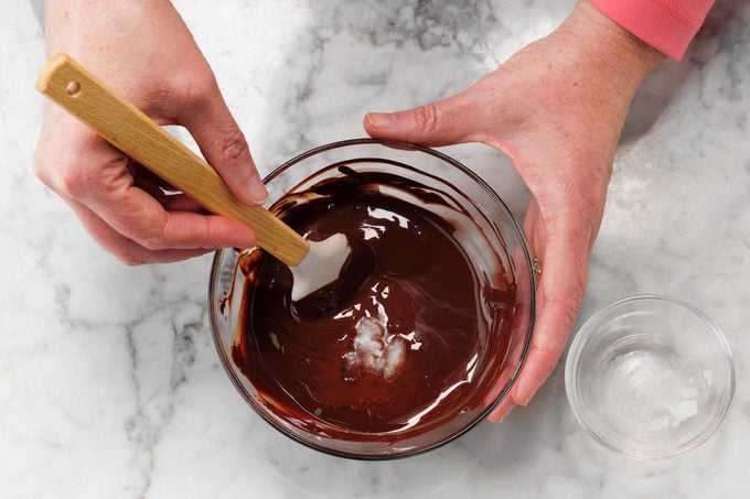 A close-up view of someone stirring melted chocolate.