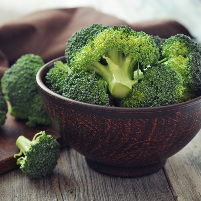 Bunch of fresh green broccoli on brown plate over wooden background