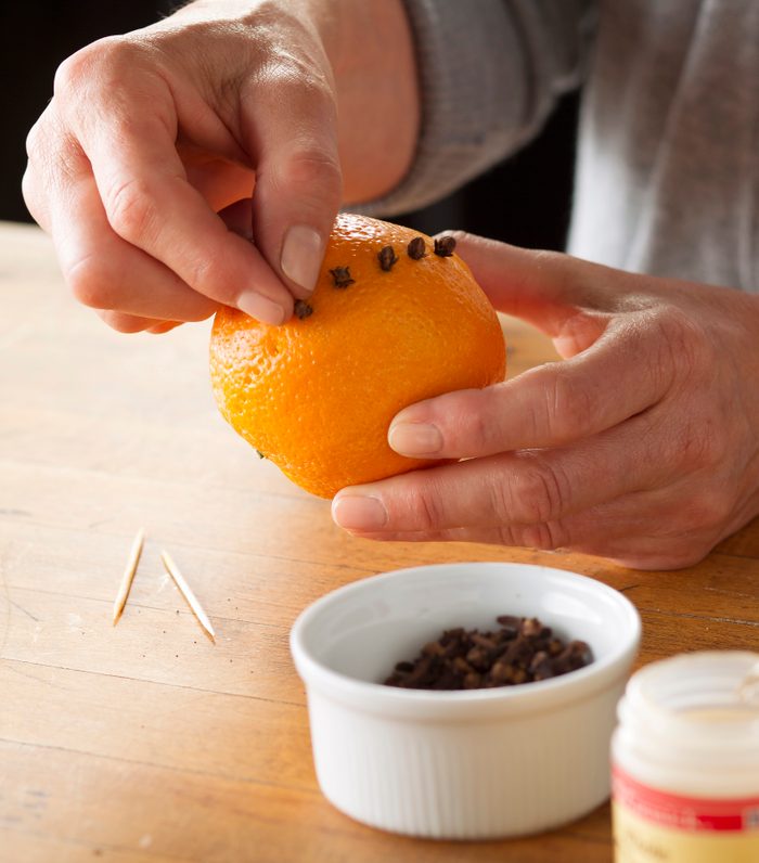 Inserting whole cloves into an orange.