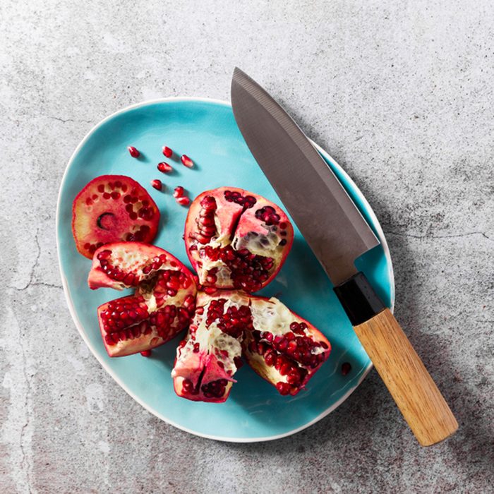 cut ripe red pomegranate on a plate on a stone table.