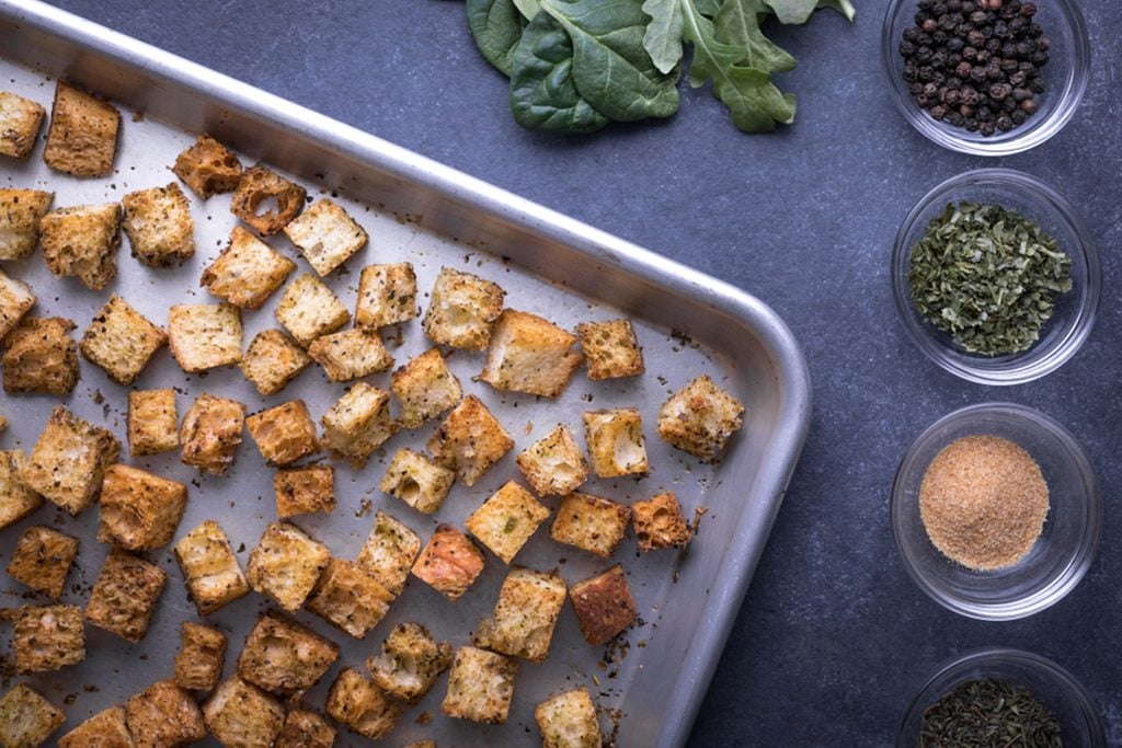 Top down view on baked bread croutons in the corner of a metal rimmed baking sheet