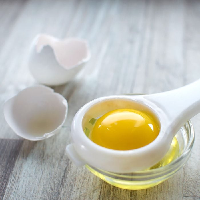 Separating egg white and yolk on wooden table and broken egg shells are at background; Shutterstock ID 1120967897; Job (TFH, TOH, RD, BNB, CWM, CM): Taste of Home