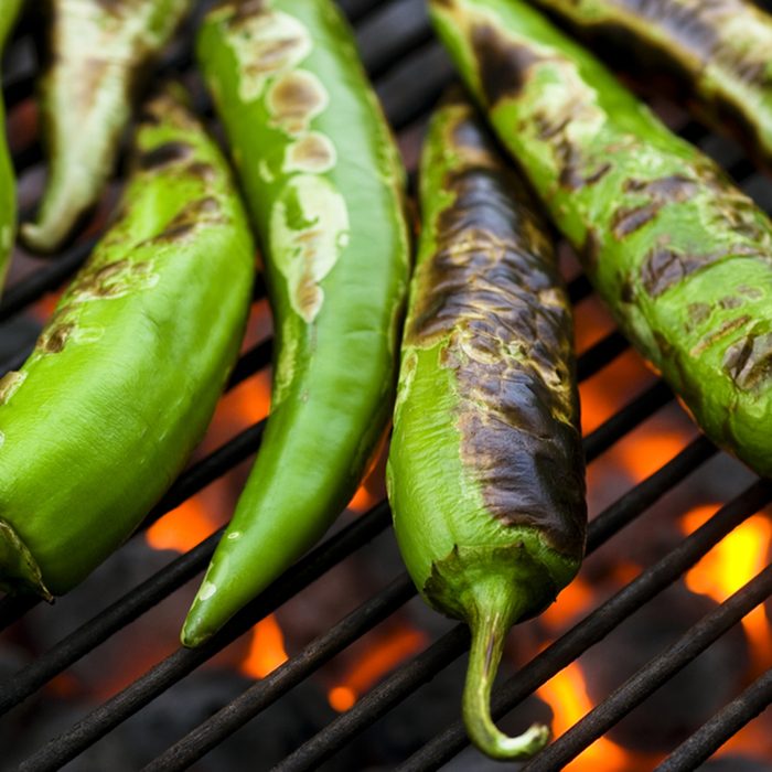 Fresh anaheim chili peppers roasting over a charcoal grill