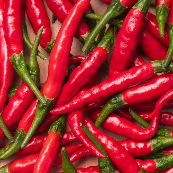 Fresh red hot thai chili peppers on wooden surface