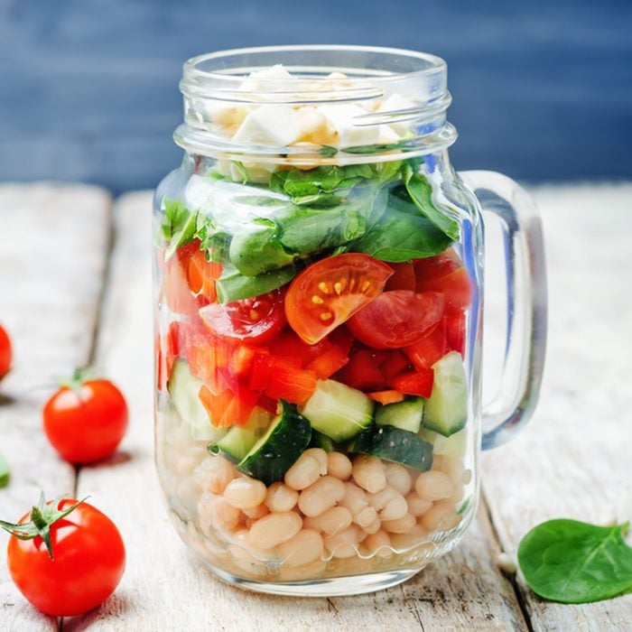 White beans cucumber tomato red pepper feta spinach salad in a jar. 