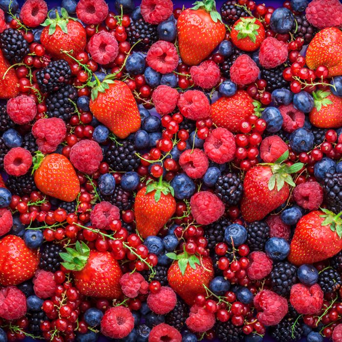 Berries overhead closeup colorful assorted mix of strawberry, blueberry, raspberry, blackberry, red currant in studio on dark background