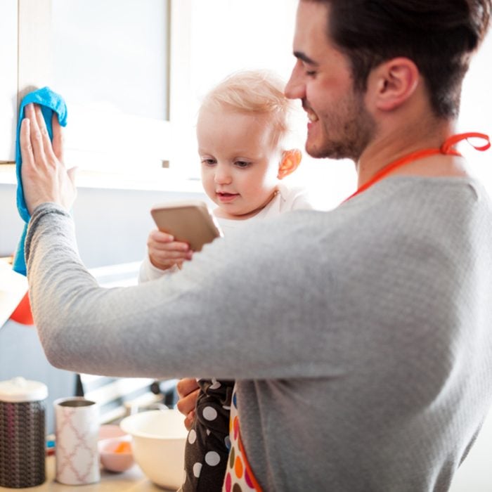 Modern Masculinity, young father with his little daughter on hand cleaning kitchen