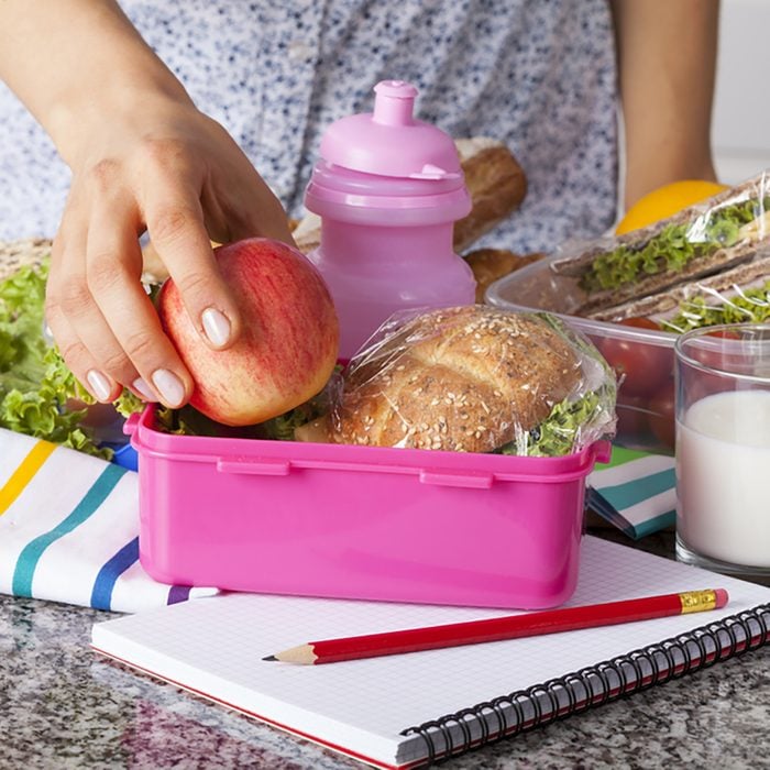 Woman preparing lunchboxes with fruits and sandwiches for school