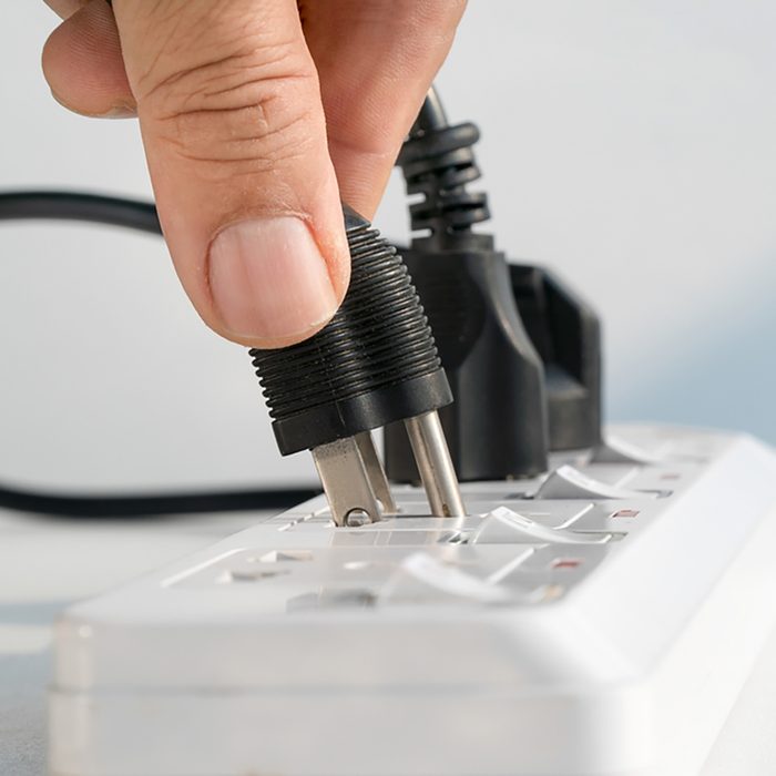 Close up Elderly hand plugging into electrical outlet;