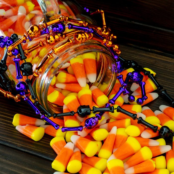 Halloween background of jar of candy corn and an assortment of voodoo bead on a dark wooden table.