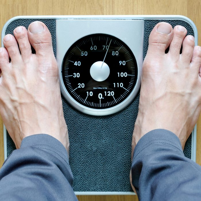 Legs of men standing on scales weight background fitness room.