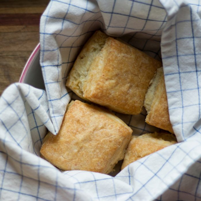 Freshly baked American biscuits in a kitchen towel and bowl