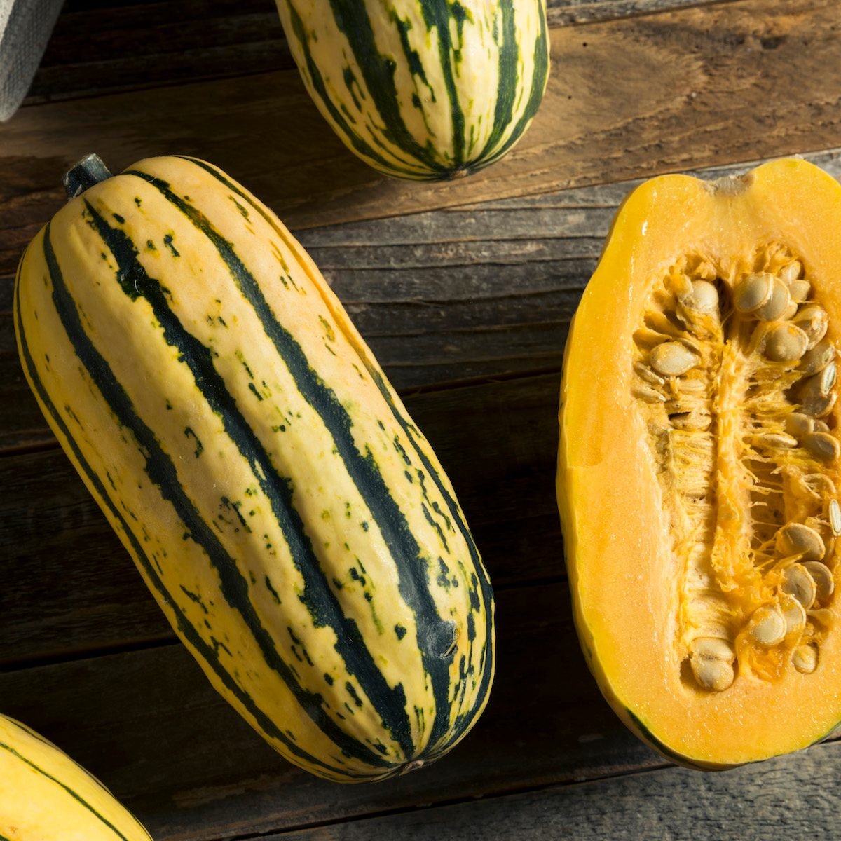 Two deliata squash—one whole and one sliced in half vertically.