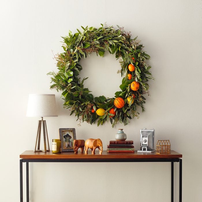 A beautiful wreath of greens and mixed fresh citrus over a foyer table.
