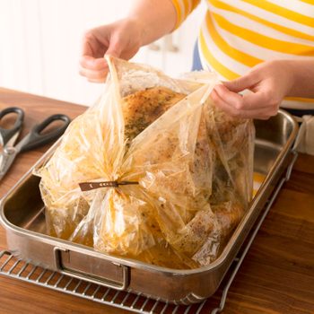 opening an oven bag to reveal the cooked turkey inside