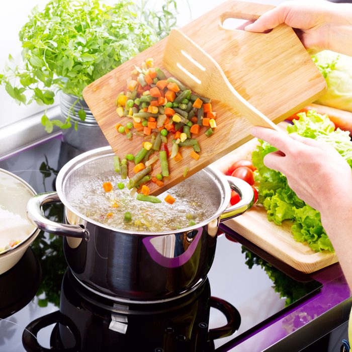 female hands cooking vegetable soup in the kitchen