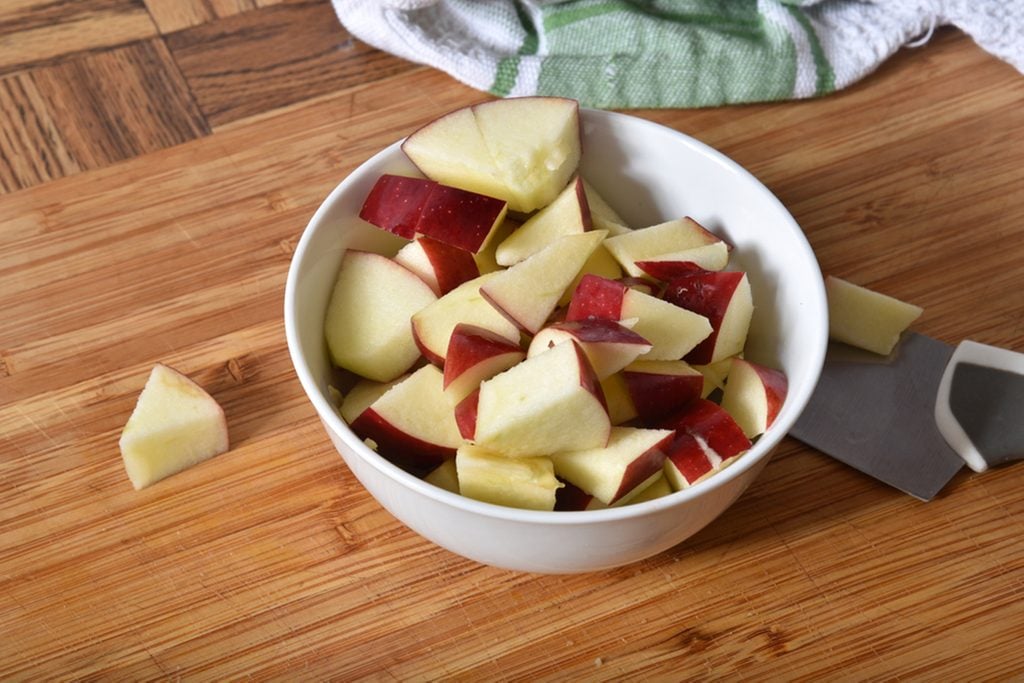 A bowl of diced apples on a cutting board