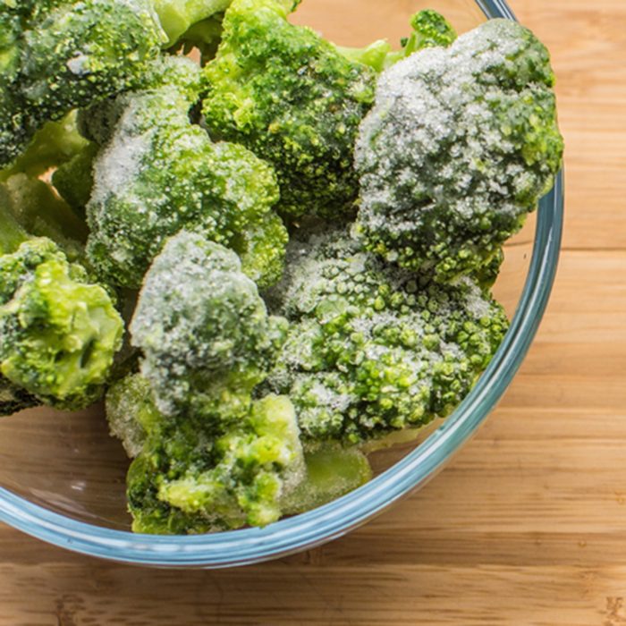 Frozen broccoli in a glass bowl on a wooden surface