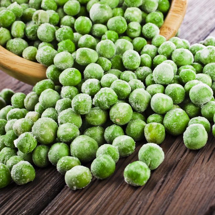 Heap of frozen pea on a old wooden table