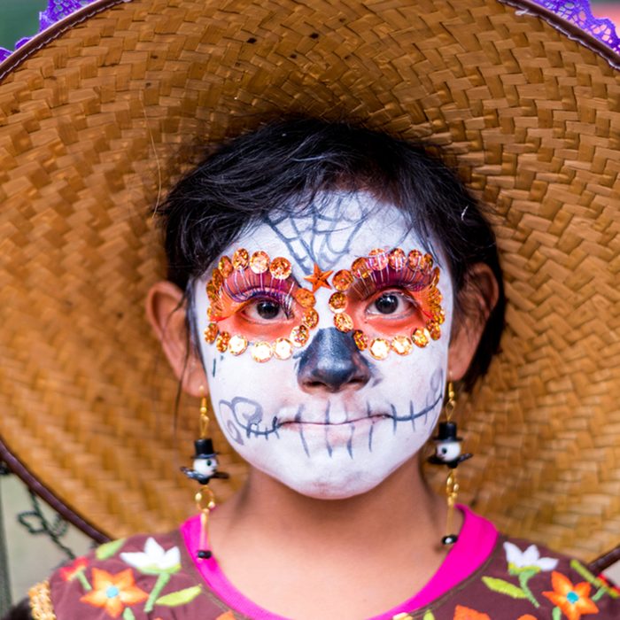 Girl with a skull paint on face participate in a Parade of Day of the dead