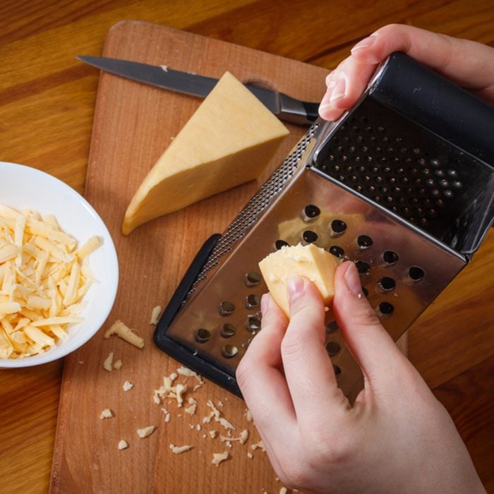 The girl is rubbing Dutch cheese on a grater