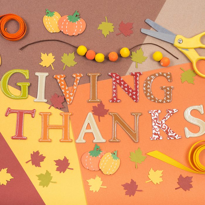 Colorful accessories for Thanksgiving holiday craft - paper, letters, scissors, ribbon, beads. View from above