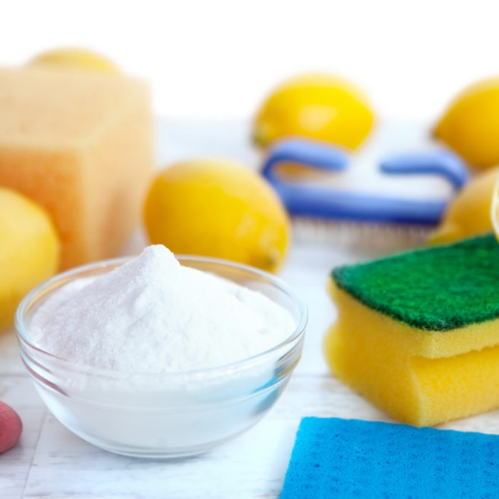 Cleaning accessories with baking soda,sponges and lemon on wooden surface