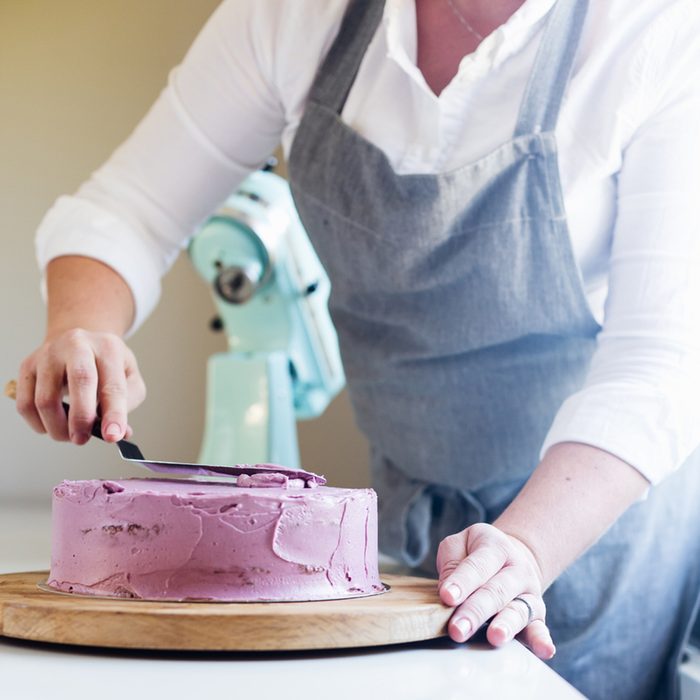trim the cream icing on a lilac cake with a spatula; Shutterstock ID 411716662; Job (TFH, TOH, RD, BNB, CWM, CM): Taste of Home