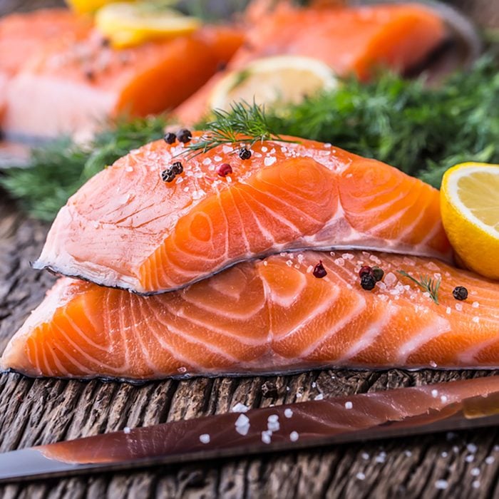 Raw salmon fillets pepper salt dill lemon and rosemary on wooden table