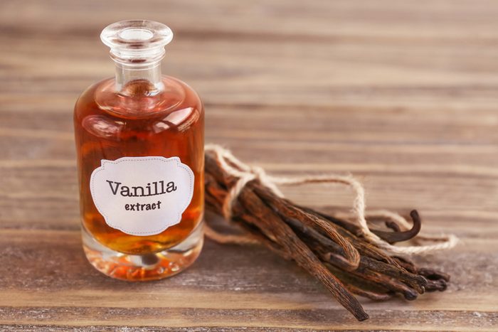 Bottle with aromatic extract and dry vanilla beans on table; Shutterstock ID 700819798
