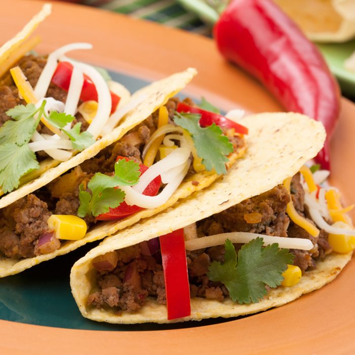 Assorted Mexican dishes, with whole grain corn beef tacos as the main subject.