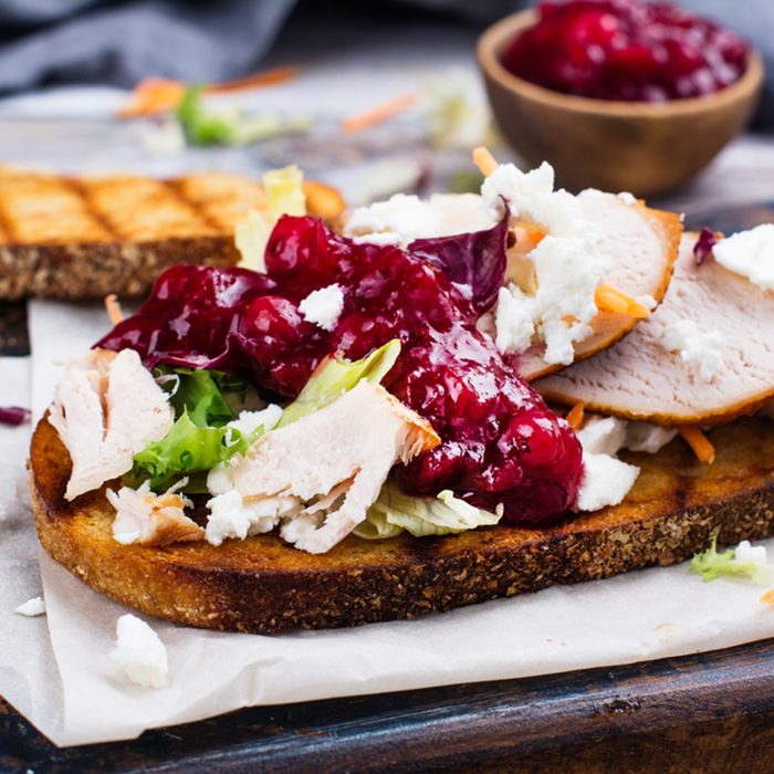 Homemade leftover thanksgiving day sandwich with turkey, cranberry sauce, feta cheese and vegetables