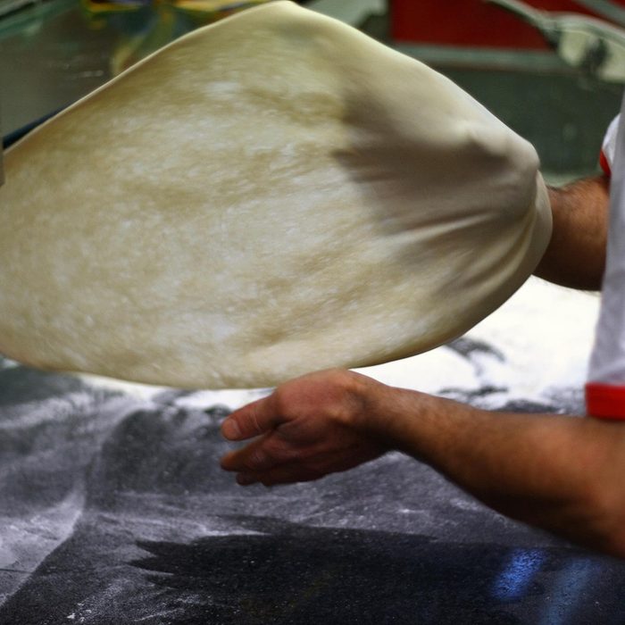 Man flipping pizza dough
