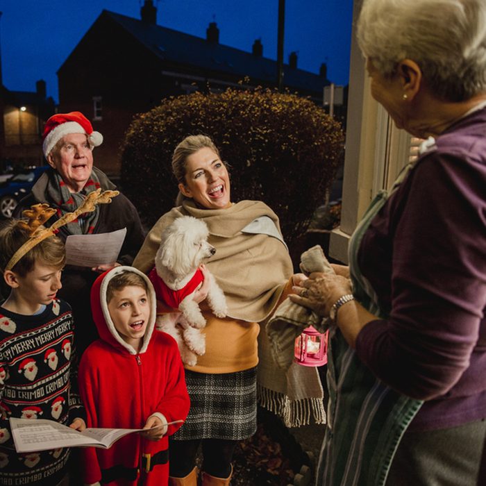 Three generation family are doing door-to-door carol singing. There is a senior woman at the door, appreciating their singing.; Shutterstock ID 672017275; Job (TFH, TOH, RD, BNB, CWM, CM): TOH