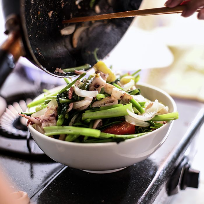 Happy housewife cooking squid with seafood in home kitchen