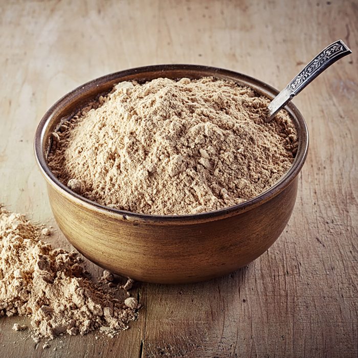 Bowl of maca powder on wooden background