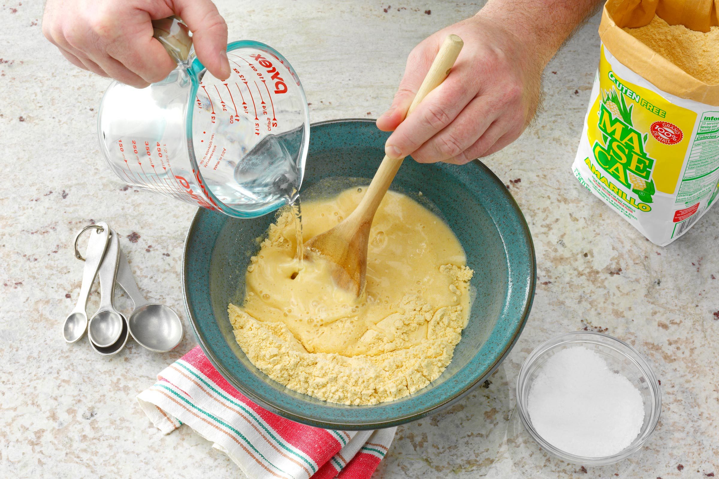 person adding ingredient to a bowl to make the dough for Corn Tortillas