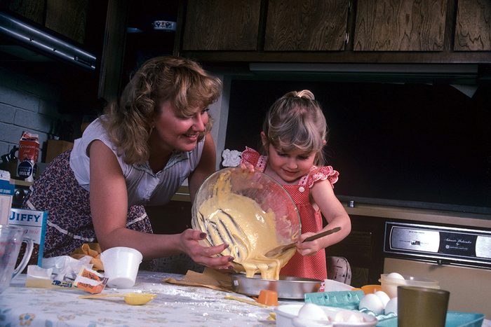 Child cooking helped by her mother