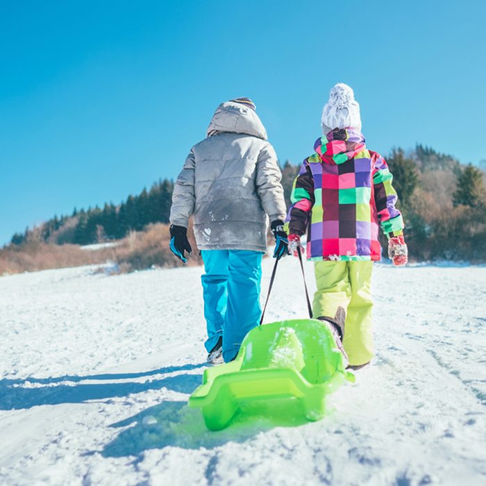 Little boy and girl carry the sled and enjoying winter sledding time