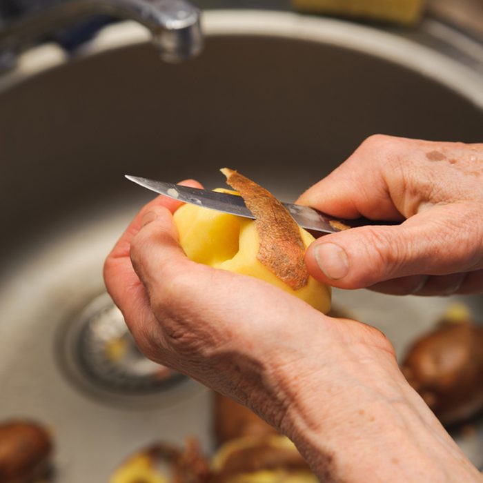 Elderly woman to peel potatoes.