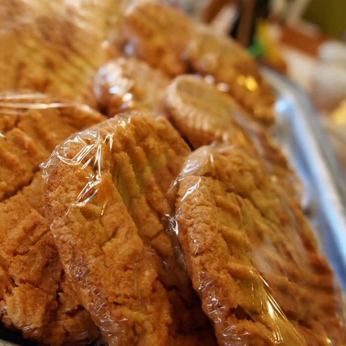 Freshly baked peanut butter cookies in plastic wrap at a coffeehouse bakery counter.