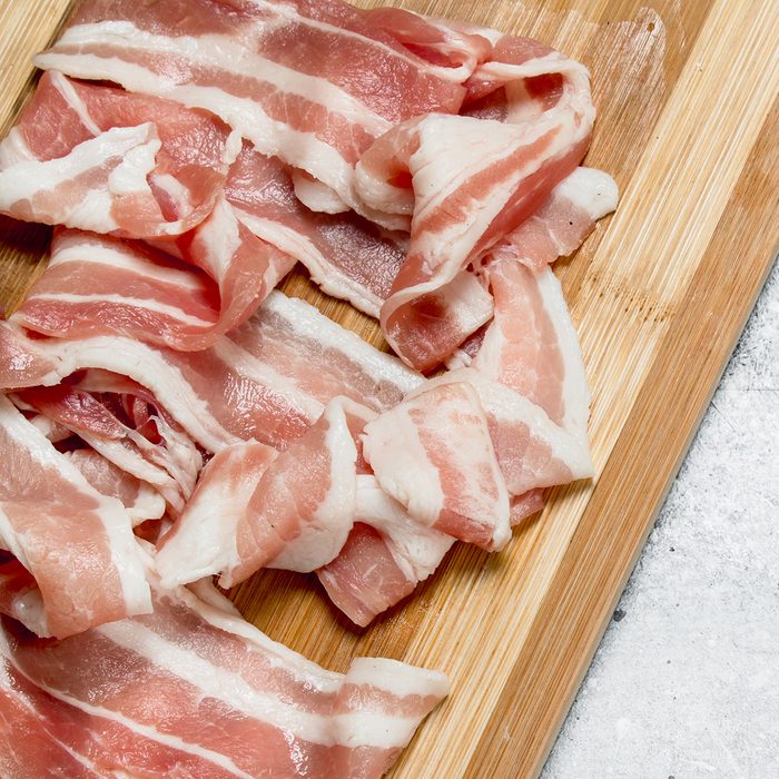 Raw bacon on the Board. On a rustic background.
