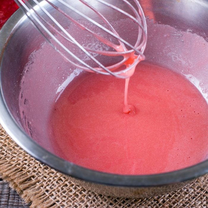 Preparation of pink icing in a bowl on the table
