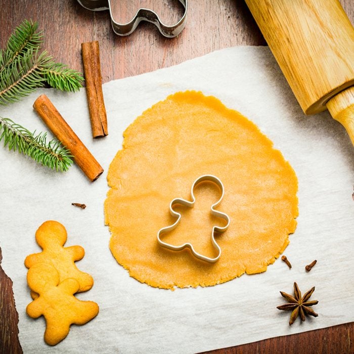 Gingerbread cookies, cookie dough and Christmas decorations on wooden table