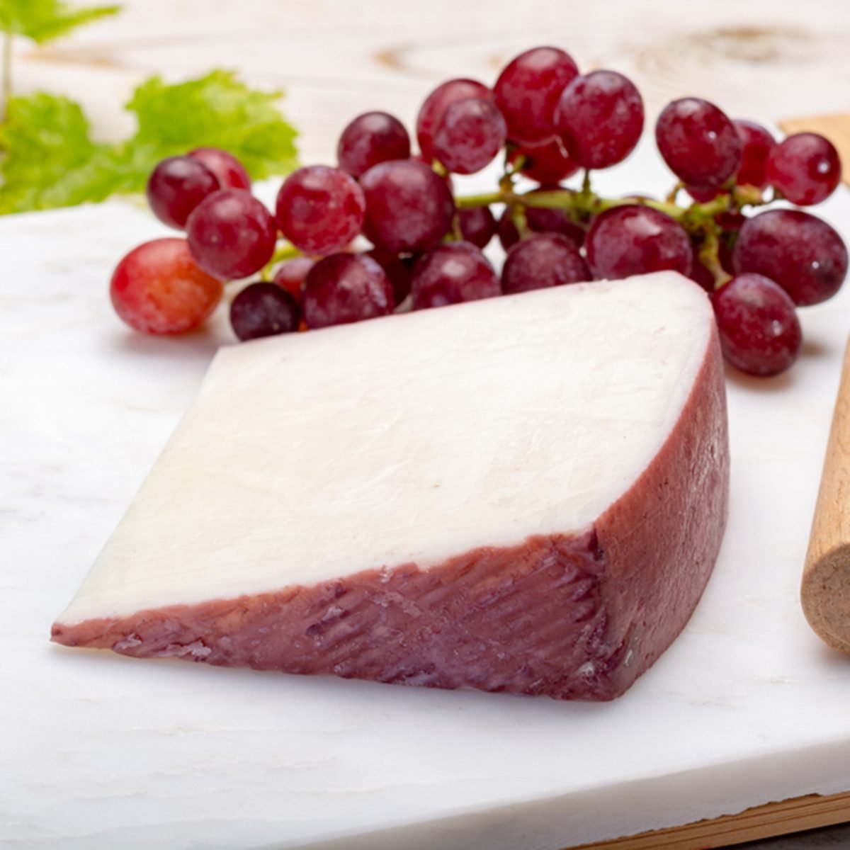 Traditional Spanish cheese, one piece of Murcian wine cheese from goat milk with rind washed in red wine, served with fresh ripe grapes