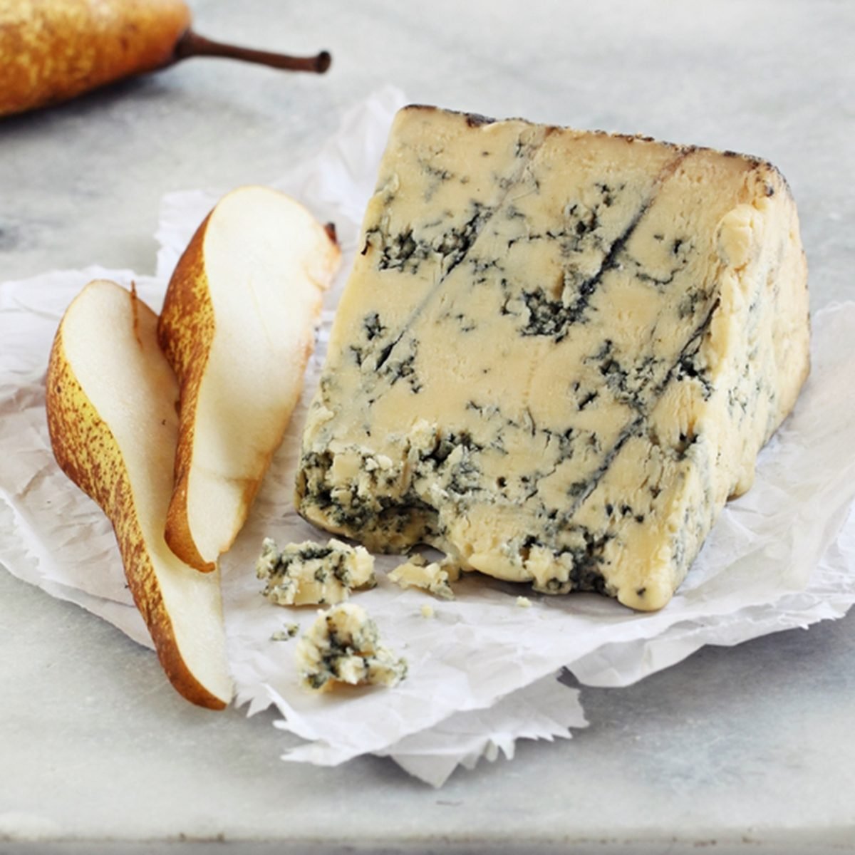 Blue cheese and pear on a marble cutting board. Old english Stilton cheese.