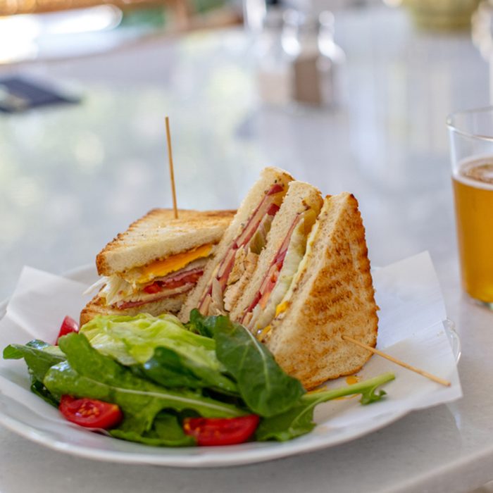 Club Sandwich with a Glass of Beer on a Table. Fast food.