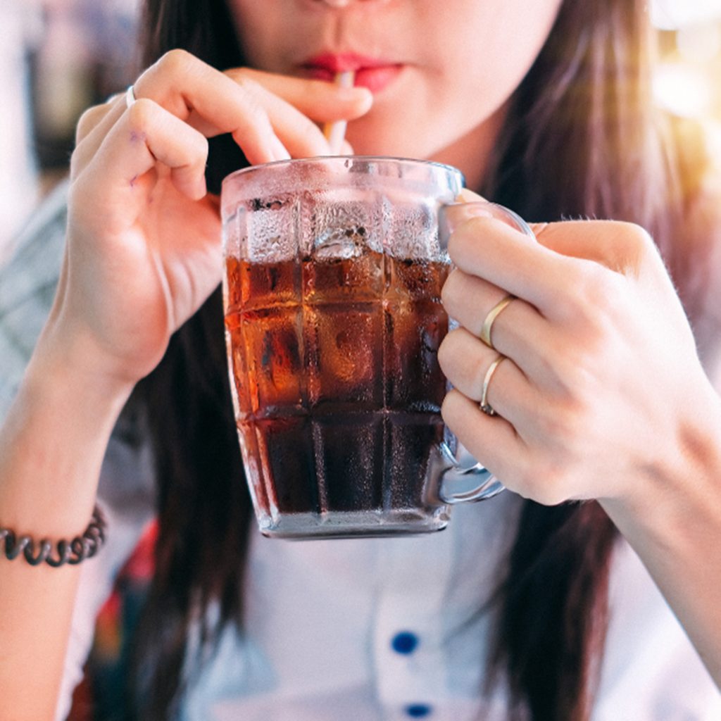 closeup woman drinking ice cola in the glass.