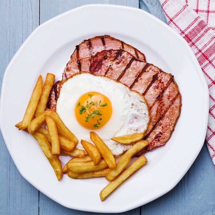 English breakfast with grilled ham, fried egg and french fries.