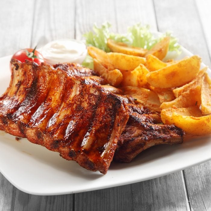 Close up Gourmet Main Dish with Grilled Pork Rib and Fried Potatoes on White Plate.
